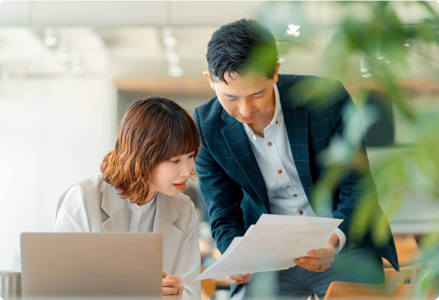 オフィスで書類を見ながら打ち合わせをする男女のビジネスパーソン